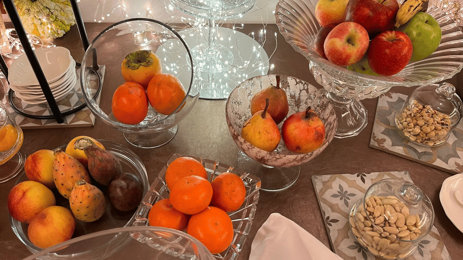 verschiedene Glasgefäße mit Khaki-Frucht, Pfirsich, Kaktusfeige, Orangen, Birnen, Äpfel, Bananen, Nüsse in den Farben changierend von dunkelrot bis hellgelb