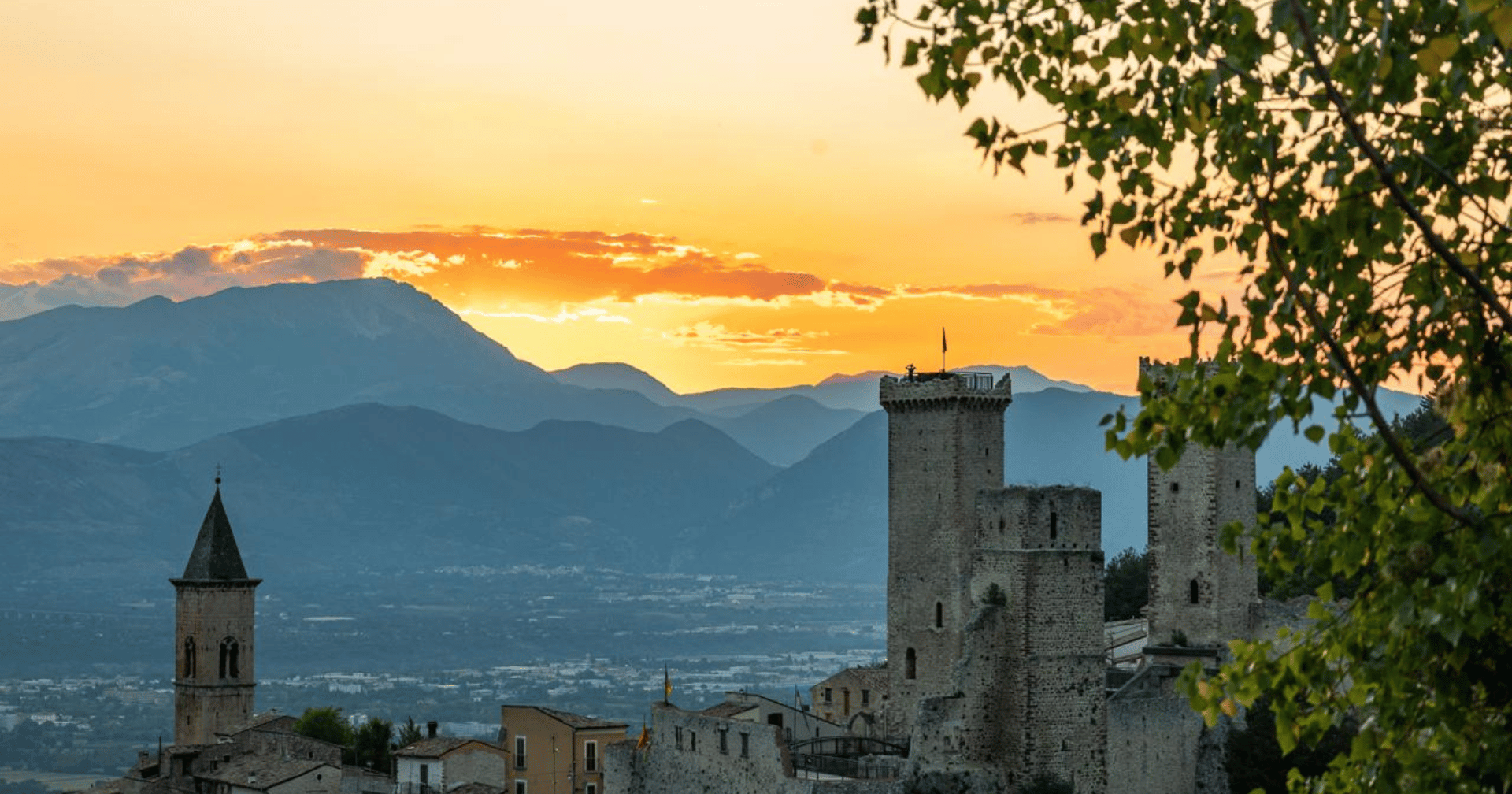 Abendstimmung über einer italienischen Stadt mit Burgtürmen und Berglandschaft